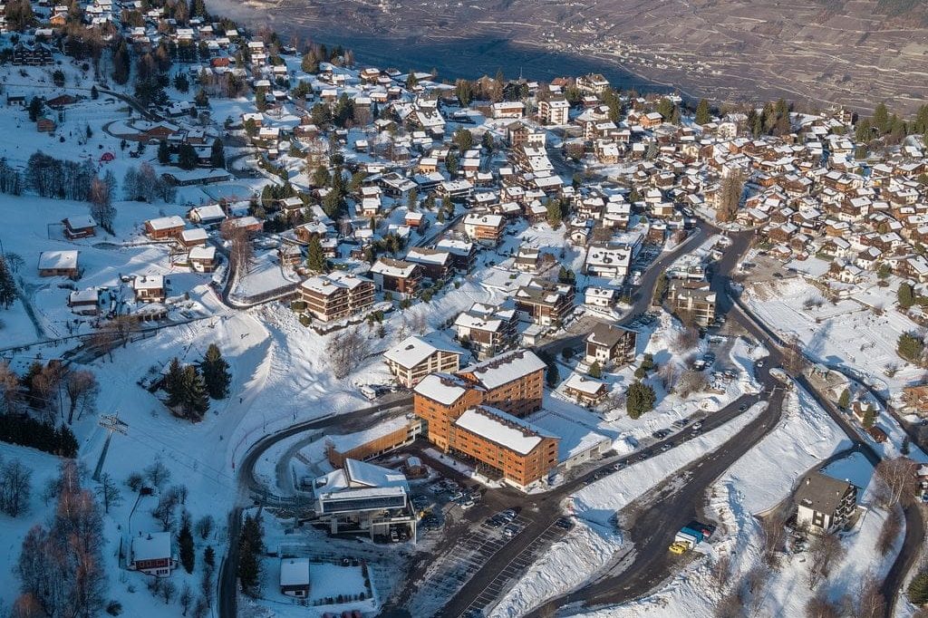 Alpejska miejscowość z lotu ptaka: zabudowa, wyciąg i stoki tuż przy domach