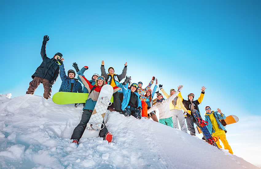 Duża grupa narciarzy i snowboardzistów świętuje na szczycie stoku